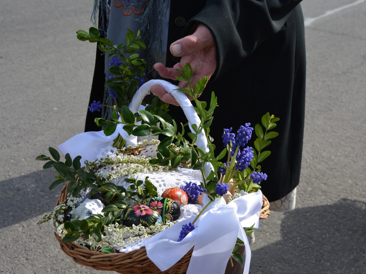Udekorowany bukszpanem koszyk wielkanocny, przymany w ręce.