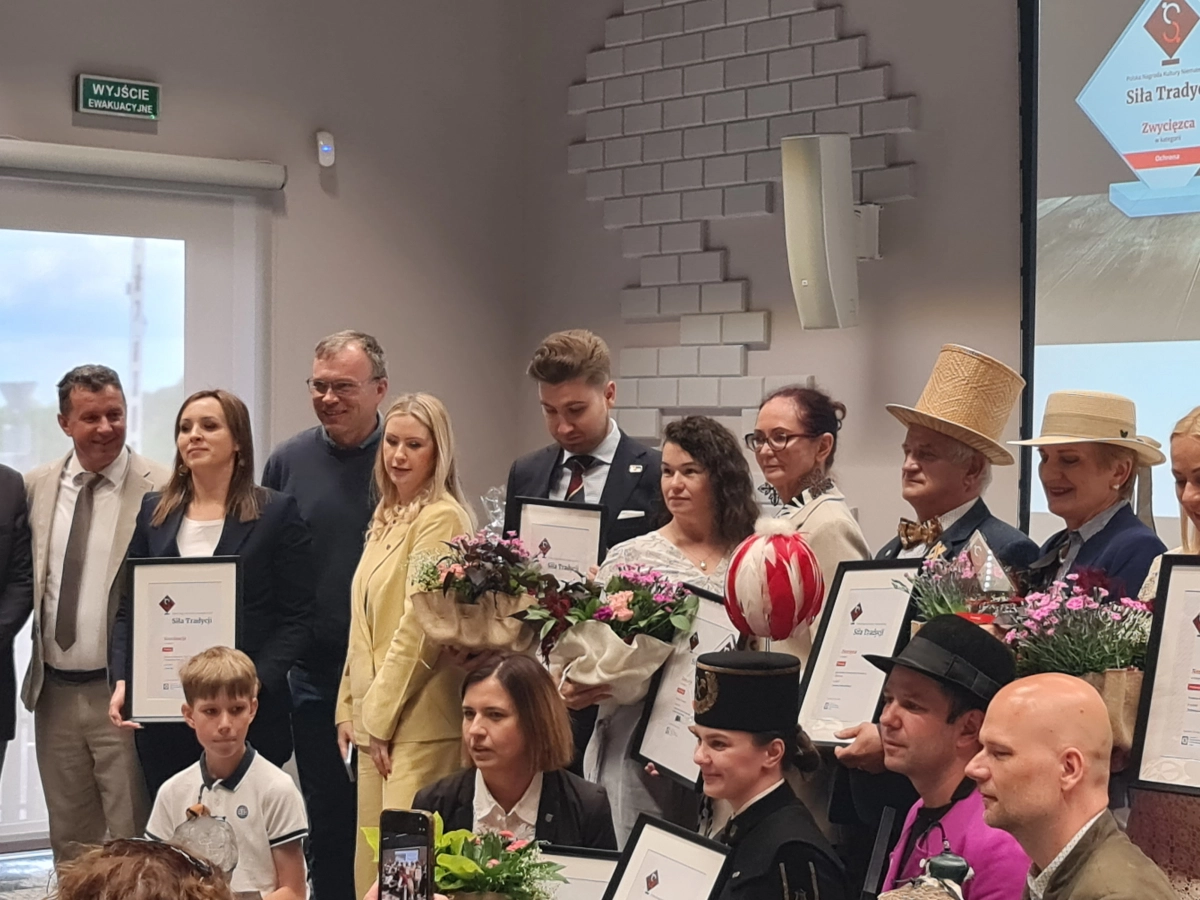 Laureaci konkursu pozują do wspólnego zdjęcia z dyplomami i kwiatami podczas uroczystości wręczenia nagród za działania na rzecz dziedzictwa kulturowego.
