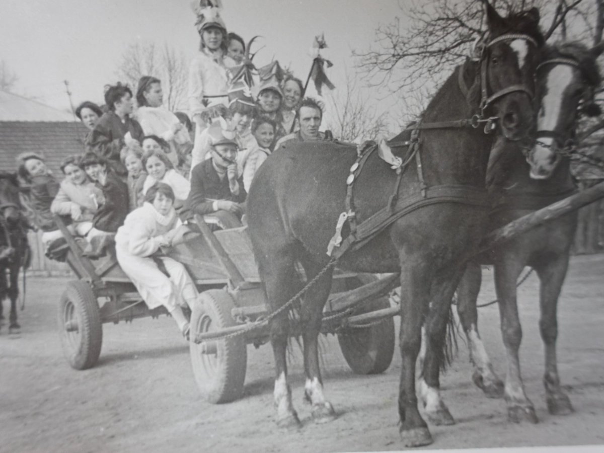 Archiwalne zdjęcie powozu z dużą grupą dzieci i dorosłych ciągniętego przez parę koni.
