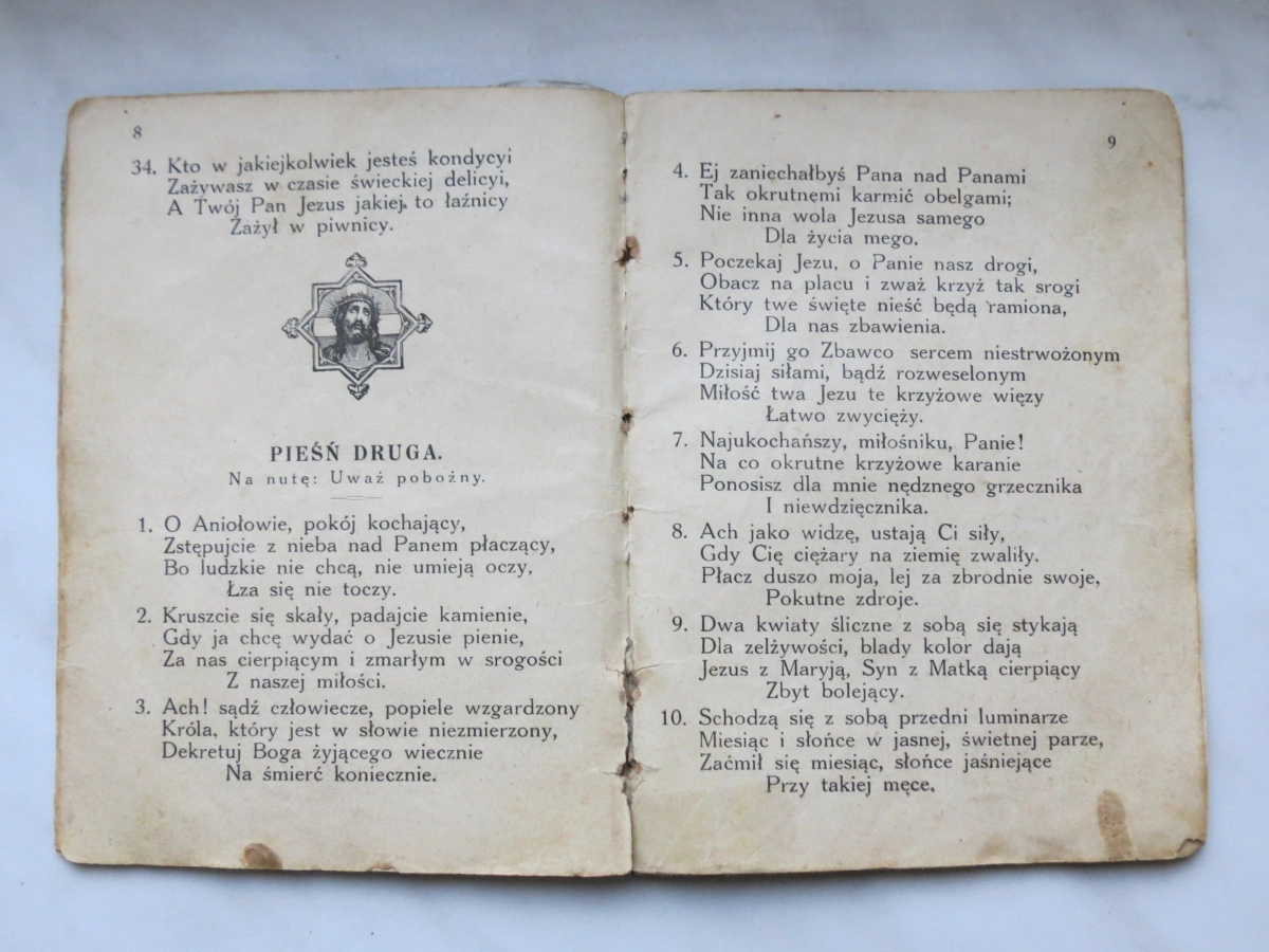 Wnętrze starego śpiewnika. Na pożółkłym papierze tekst i grafika przedstawiającą Jezusa Chrystusa.