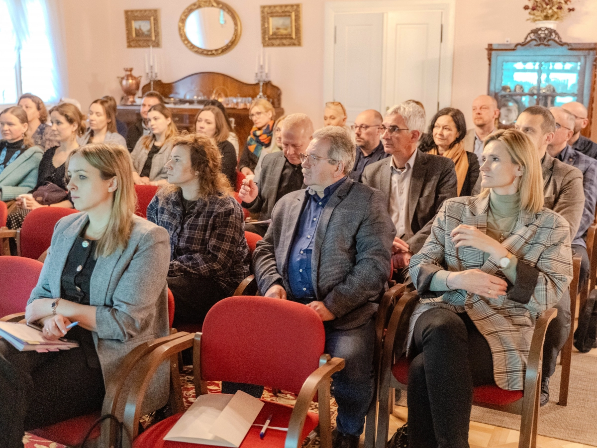 Grupowe zdjęcie publiczności siedzącej w elegnckim pomieszczeniu.